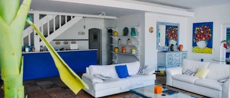 Ein Wohnzimmer mit einem weißen Sofa, einem Couchtisch und einer Treppe, die in einen Küchenbereich führt.
