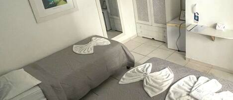 A hotel room with two beds, a wardrobe, a desk, and a TV.