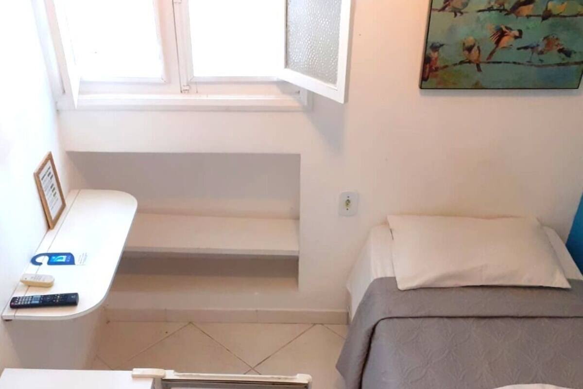 A small, clean room with a bed, a desk, and a window.