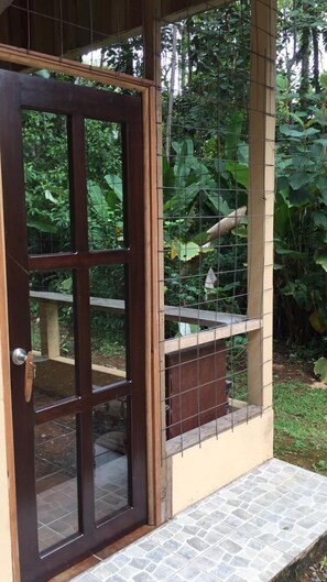 Una puerta de madera con un panel de vidrio, una valla de metal y una plataforma con baldosas de piedra.