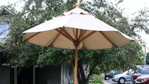A patio with a table and chairs, an umbrella, and a lawn. - Boyne City Motel (Boyne City)