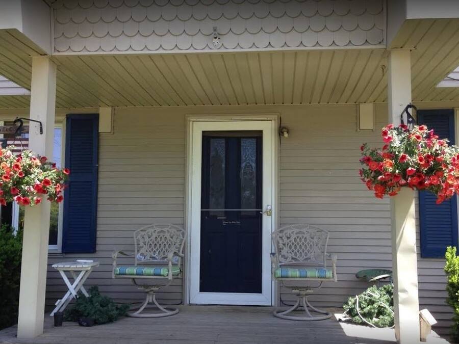 A porch with two wicker chairs, a small table, and a door with a window above.