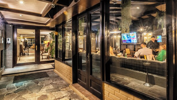 Ein modernes Restaurant mit einem Kieselstein-Belag im Eingangsbereich, großen Fenstern und innenliegender Sitzgelegenheit.