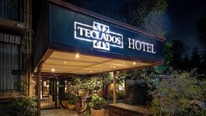 Das Außere des Teclados Hotel mit gut beleuchtetem Eingang, Steinböden und Pflanzgefäßen.