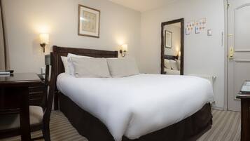 A hotel room with a large bed, bedside lamps, a wooden nightstand, a desk, and a chair.