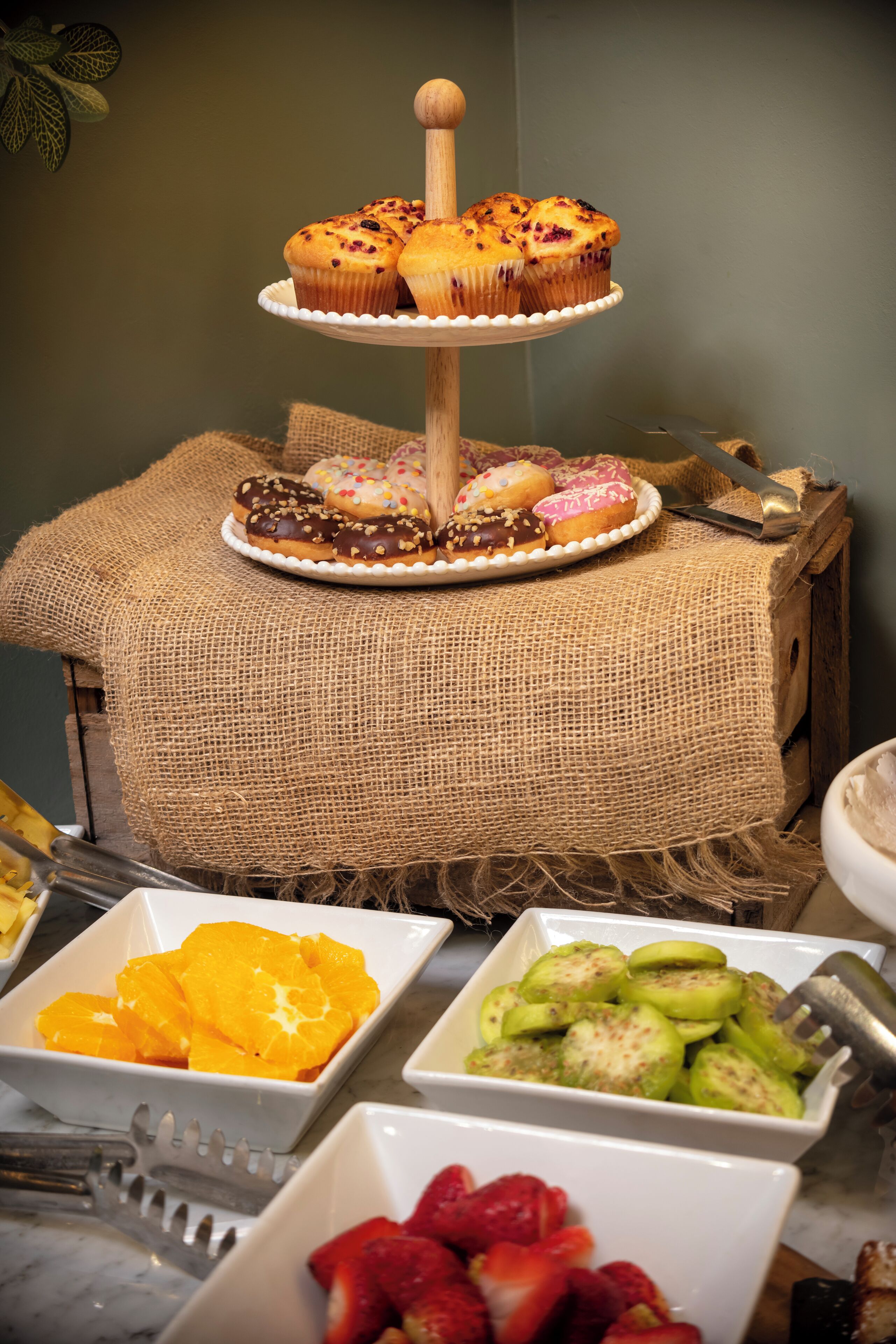 Una mesa de postres con muffins, rosquillas y fruta.