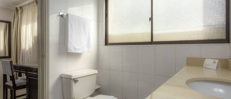 Un baño con inodoro, lavamanos y una ventana con vidrio esmerilado.