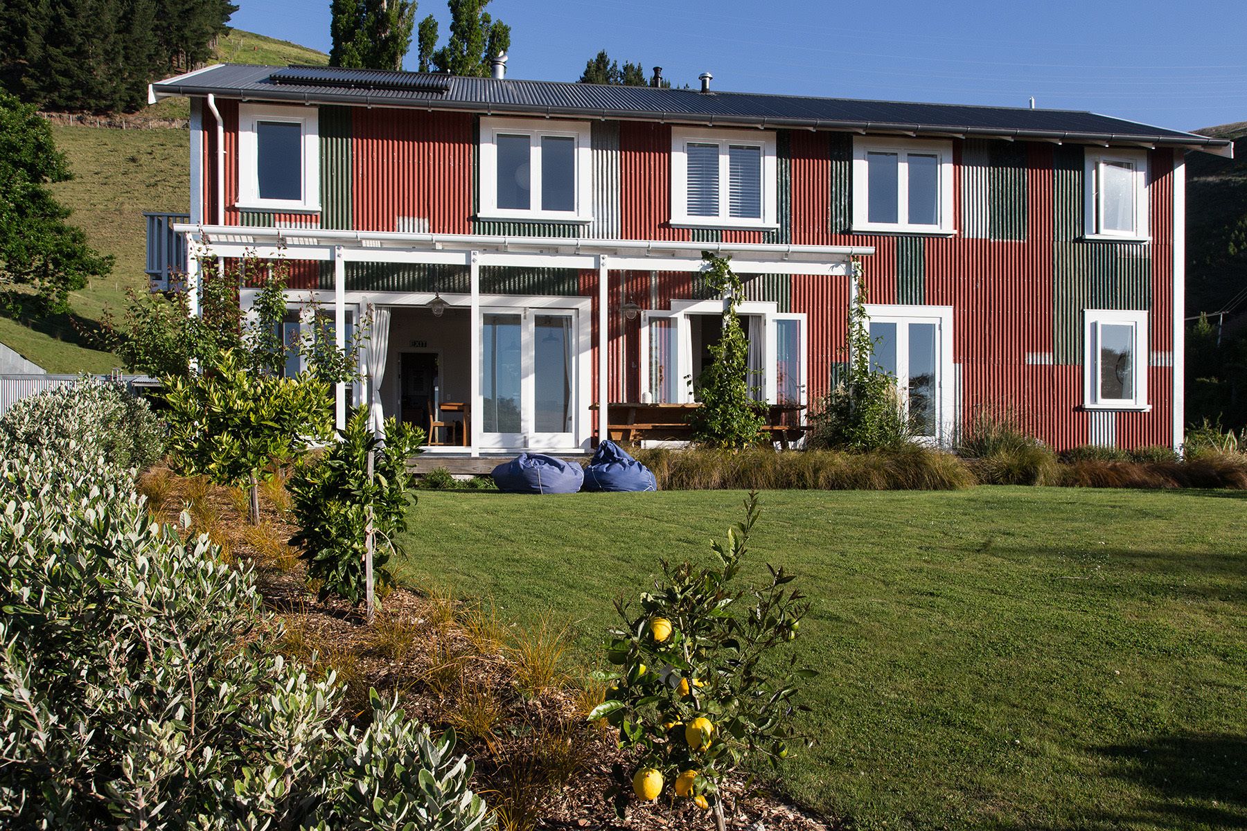 A two-story building with a red and white exterior, large windows, and a covered porch area.
