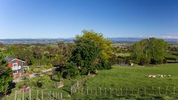 A rural landscape with a house, a fenced field, and distant mountains.
