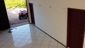 Un pasillo con piso de baldosas, una puerta roja y vista de un vehículo rojo afuera.