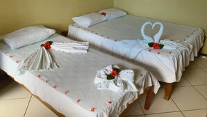 Habitación de hotel con dos camas, cada una decorada con toallas dobladas, flores rojas y una decoración de cisne con forma de corazón.