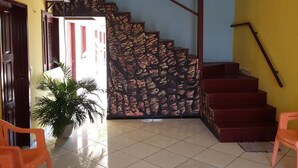 Una escalera con barandilla estampada, una planta en maceta y sillas anaranjadas.
