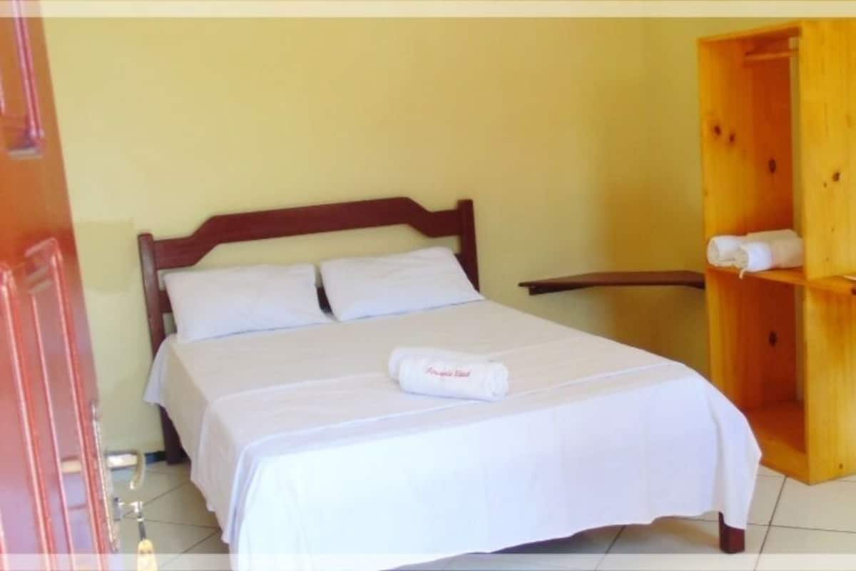 Una habitación de hotel con una cama, un armario de madera y un estante con toallas.