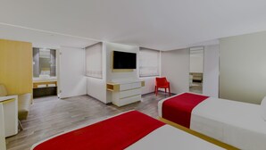 A modern hotel room with a large bed, a TV mounted on the wall, a desk, and a chair.