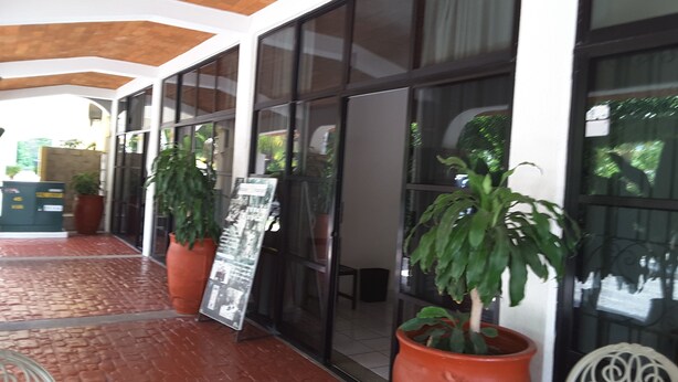 A covered outdoor area with potted plants, a seating area, and a glass wall. - Hotel Balcon Gueela (Santa María Huatulco)