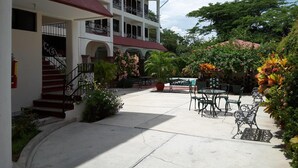 A two-story building with a covered patio area featuring outdoor seating and lush greenery. - Hotel Balcon Gueela (Santa María Huatulco)