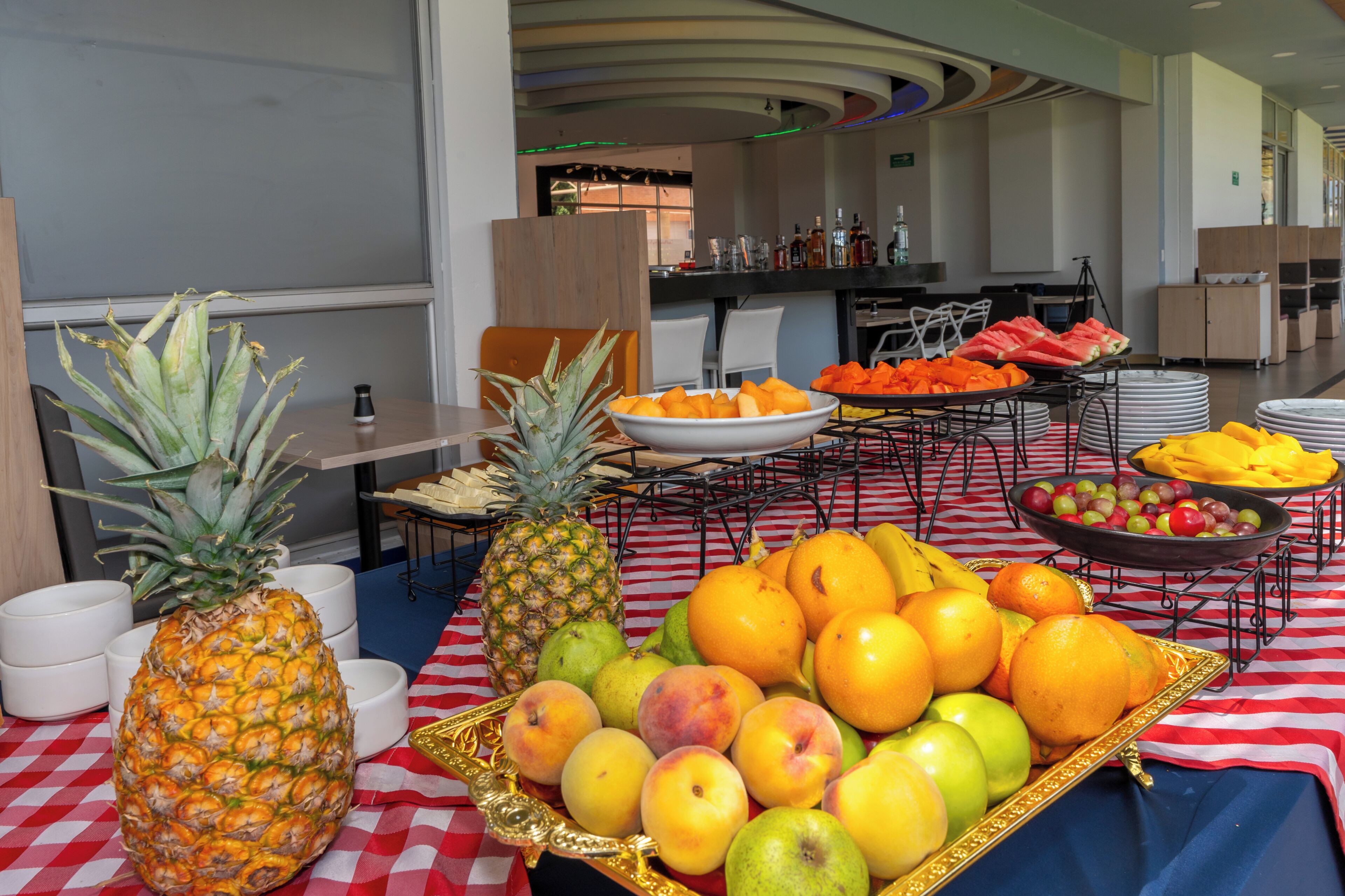 A buffet with a variety of fruits and a checkered tablecloth.