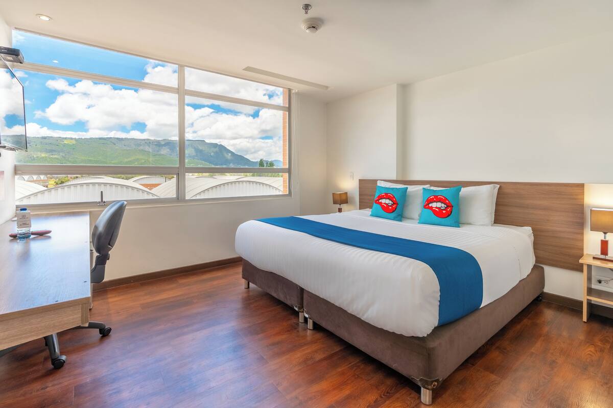 Ein Hotelzimmer mit einem großen Bett, einem Schreibtisch und Bergblick durch ein großes Fenster.