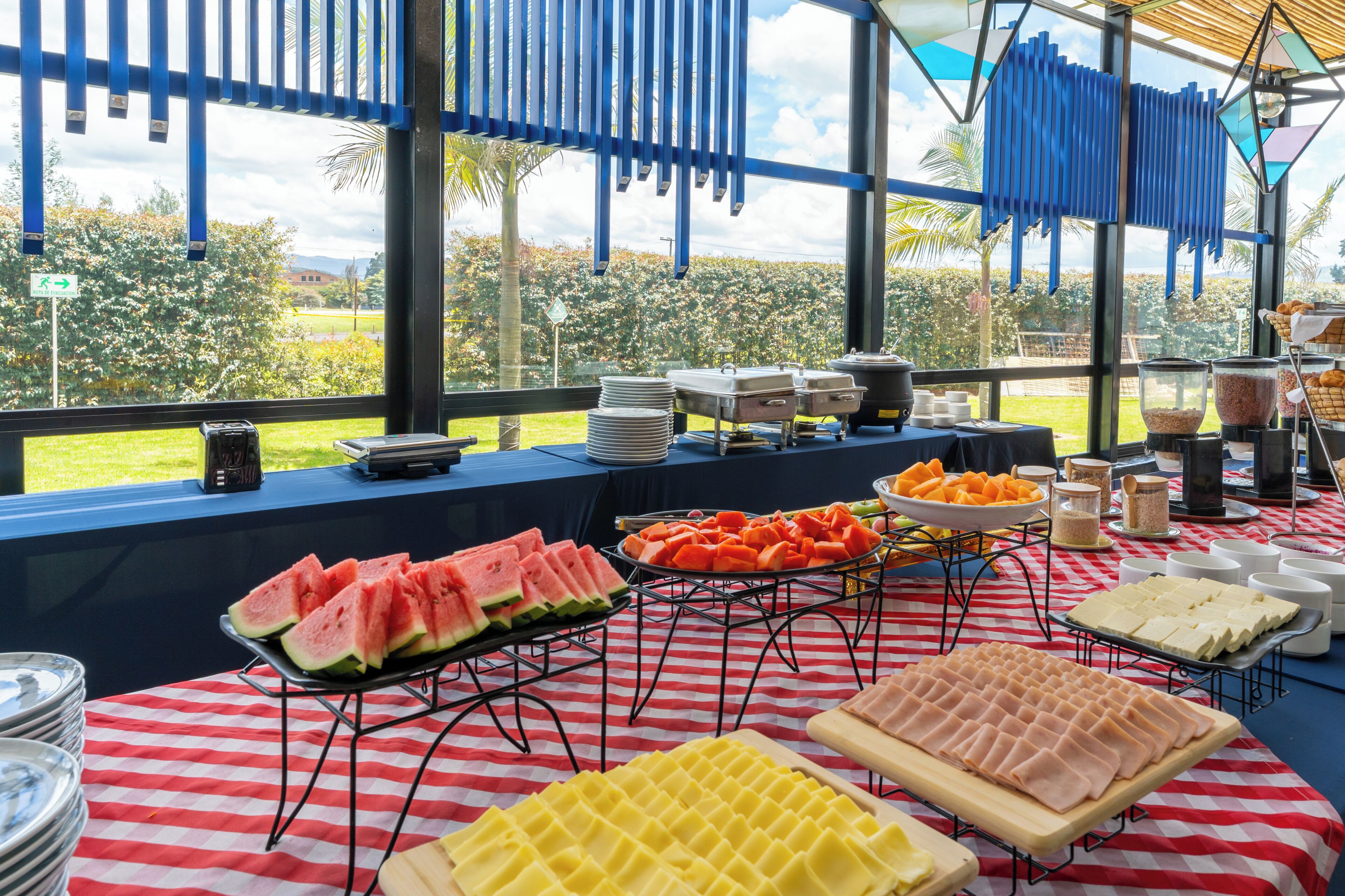 A buffet setup with various food items and serving utensils on a checkered tablecloth.