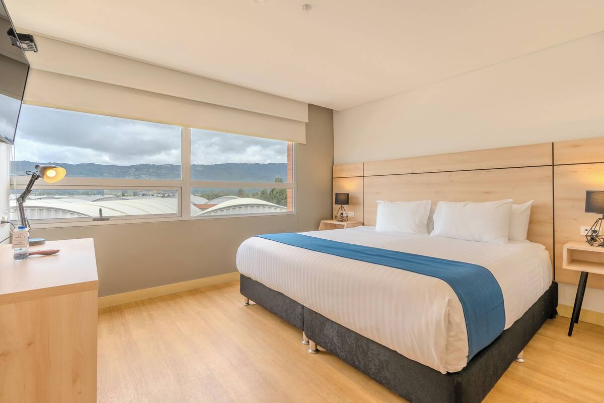 Ein modernes Hotelzimmer mit einem großen Bett, einem Schreibtisch und Bergblick durch das Fenster.