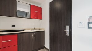 Een moderne keuken met donker houten kastjes, een rode bovenkast en een magnetron.