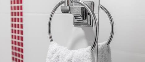 Un baño con un aro para toallas y una toalla blanca colgada.