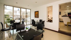 A modern conference room with glass tables and black chairs, a painting on the wall, and a view through large windows. - Casa Quinta Hotel Embajada (Bogotá)