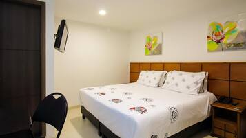 Una habitación de hotel con cama, una silla, una mesita de noche y una lámpara de pared.