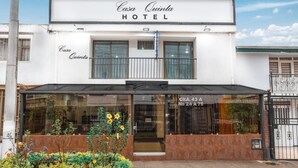 A two-story Casa Quinta Hotel with a balcony, large windows, and a well-maintained garden with yellow flowers. - Casa Quinta Hotel Embajada (Bogotá)