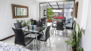 A modern dining area with glass tables and black chairs, a large mirror, and potted plants. - Casa Quinta Hotel Embajada (Bogotá)