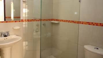 Un baño con ducha de vidrio, lavamanos e inodoro.
