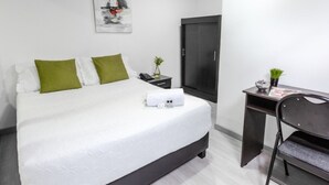A modern hotel room with a large bed, a desk, a wardrobe, and a small plant. - Casa Quinta Hotel Embajada (Bogotá)