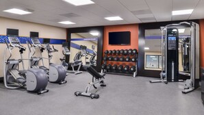 A gym with treadmills, a bench press, dumbbells, and a weight machine.