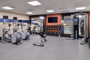 A gym with treadmills, a bench press, dumbbells, and a weight machine.