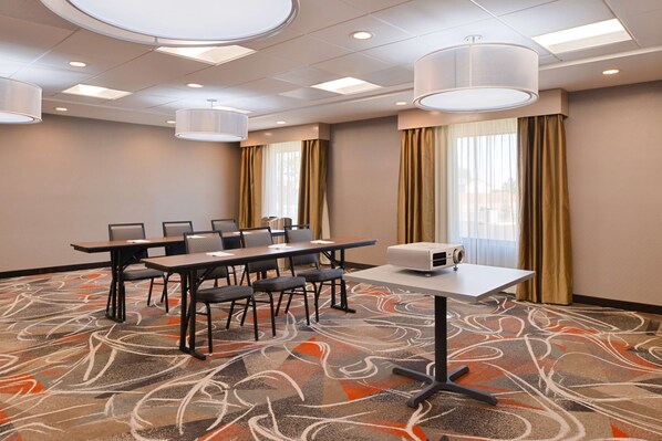 A conference room with a long table, chairs, a projector, and a carpeted floor.