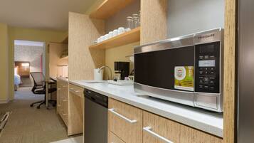 A modern kitchen with a stainless steel Frigidaire microwave, wooden cabinets, and a countertop with a coffee maker and glassware.