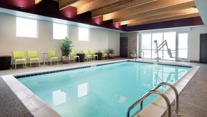 An indoor swimming pool with wooden beams, green chairs, and potted plants. - Home2 Suites by Hilton Cleveland Independence (Independence)