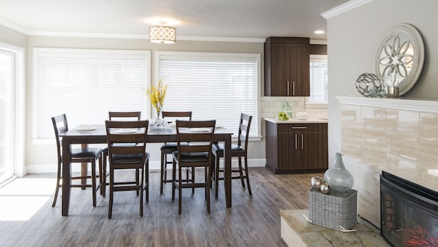 Una cocina moderna con armarios de madera, una mesa de comedor con sillas, una chimenea y un jarrón decorativo.