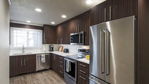 Una cocina moderna con armarios de madera oscura, electrodomésticos de acero inoxidable y un ventanal que proporciona luz natural.