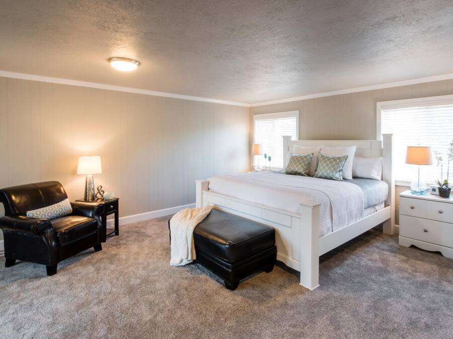 A bedroom with a bed, a nightstand, a chair, and a bench.