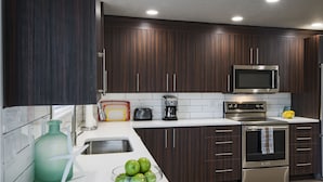 Una cocina moderna con armarios de madera oscura, electrodomésticos de acero inoxidable y encimera blanca.