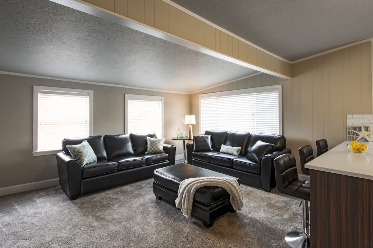 A living room with two black leather sofas, a coffee table, and a small side table with a lamp.