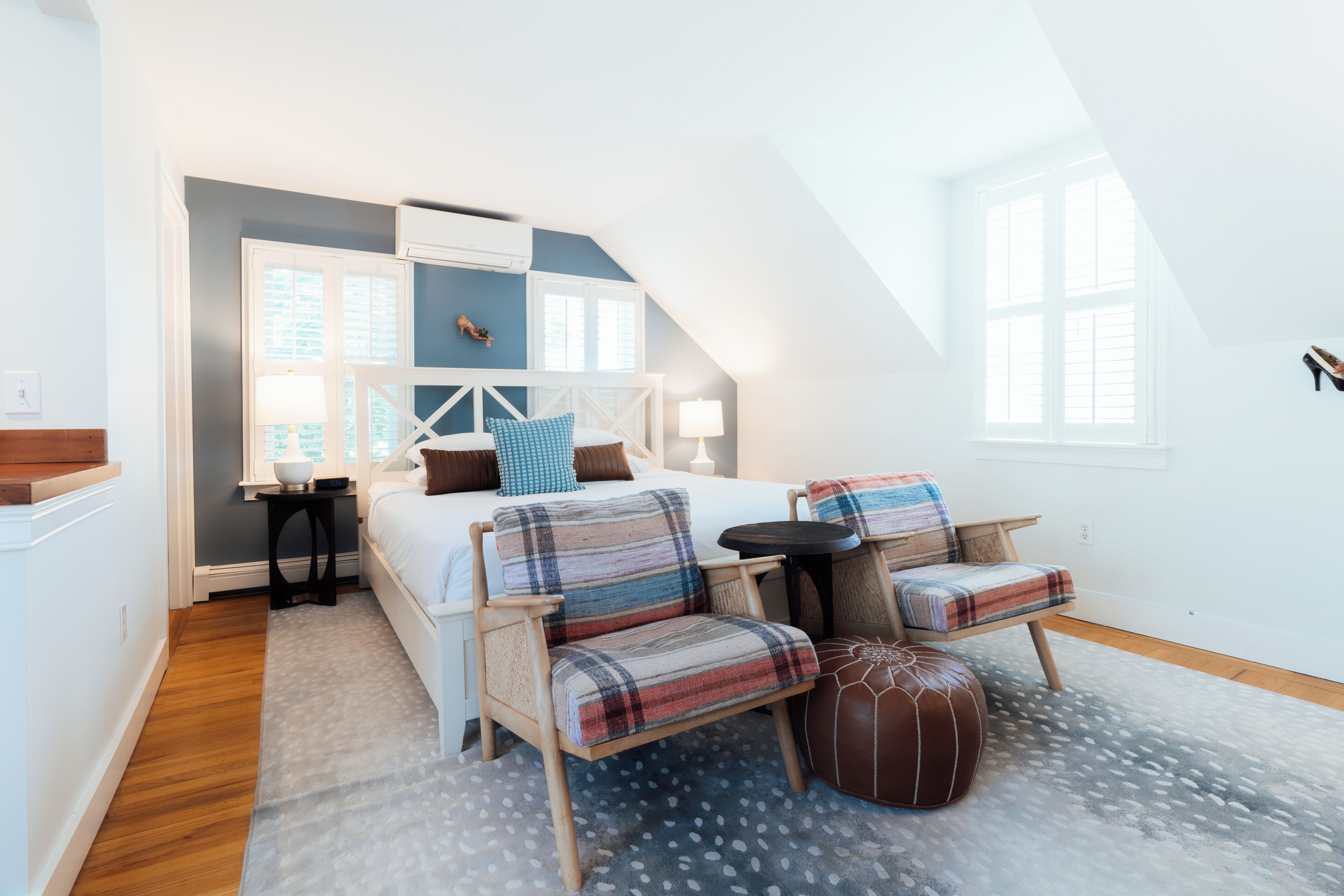 Une chambre à coucher avec un lit, deux chaises, une petite table et une fenêtre.