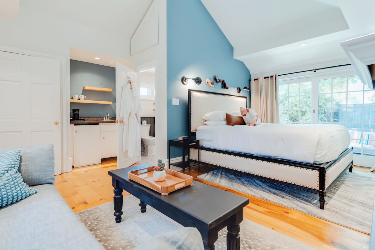 Une chambre à coucher avec un grand lit, une table de chevet, une commode et une fenêtre donnant sur un beau paysage.