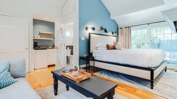 A bedroom with a large bed, a nightstand, a dresser, and a window with a view.