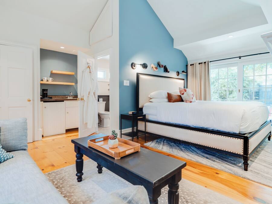 A bedroom with a large bed, a nightstand, a dresser, and a window with a view.