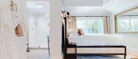 Un dormitorio con una cama grande, una mesita de noche, cortinas en la ventana y vistas a árboles.
