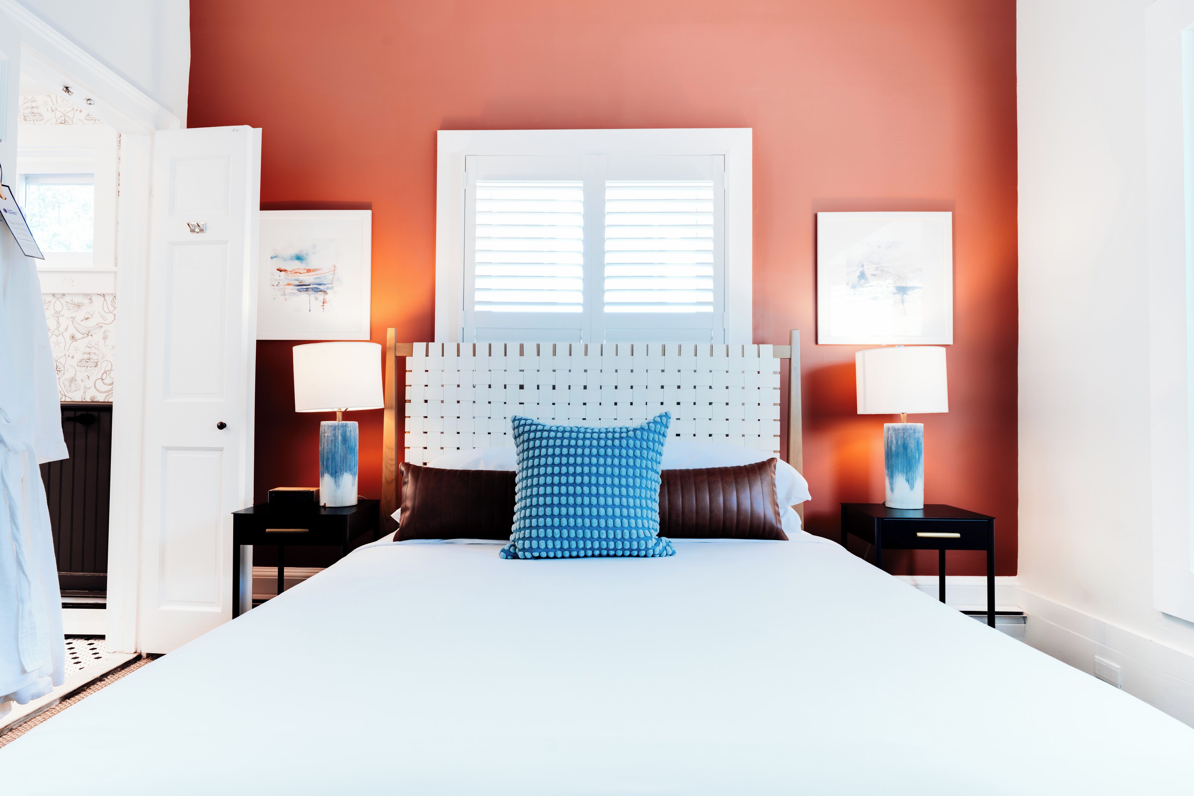 A large bed with a white headboard, two bedside tables with lamps, and artwork on the walls.