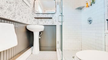 Une salle de bain avec un lavabo blanc, des toilettes et un espace douche.