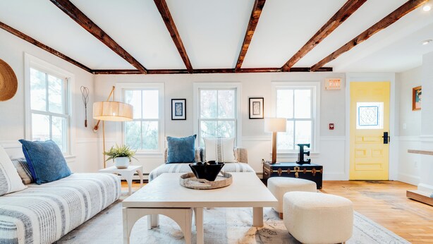 A spacious living room with a large sofa, a coffee table, and a yellow door in the background.